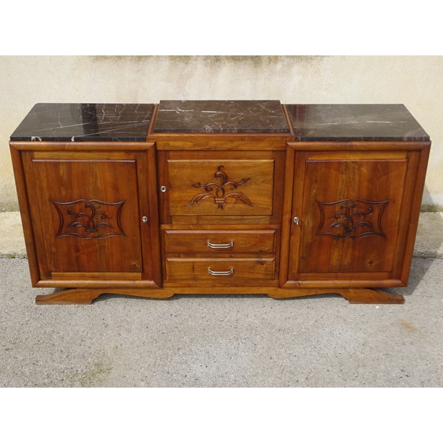 Large solid walnut sideboard with straight, rectilinear curves. Three solid wood cupboard doors with a central motif and...