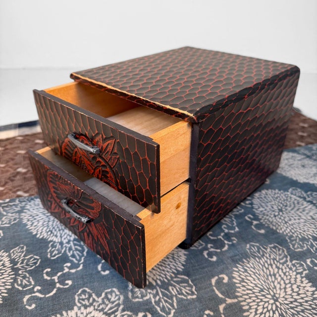 This compact box is made using the Kamakura-bori carving technique: a deep, dark surface with warm red tones revealed...