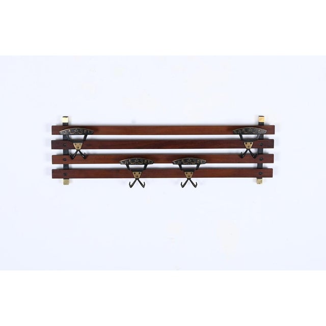 Gorgeous coat rack in teak wood, brass and enameled metal. This lovely piece was realized in Italy in the 1960s. This...