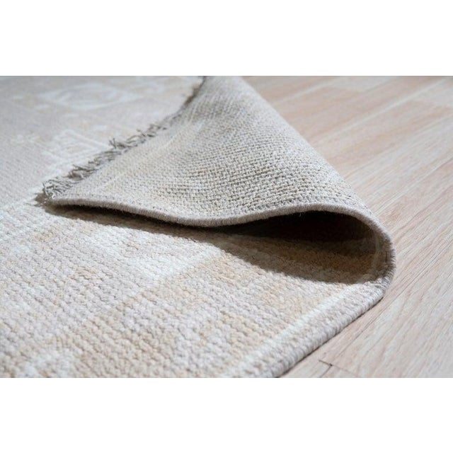 This gray wool rug features a hand knotted pile construction and originates from India. The rug presents a consistent gray...