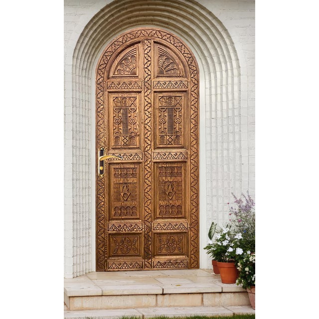 This handcrafted, arched, solid wood door features deep tribal geometric carvings across every panel, creating a dramatic...