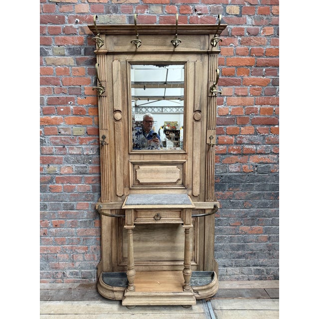 This vintage entryway coat rack made of unfinished oak has been completely restored. It features 8 brass coat hooks, a...