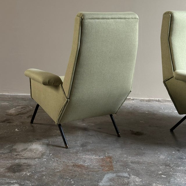 Vintage armchairs dating back to the 1950s/1960s, made in Italy. The armchairs feature a high back, black iron legs, and...