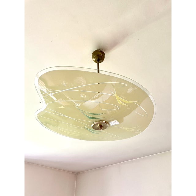 1960s saucer pendant light, gilt brass frame, asymmetrical pale yellow glass shade with transparent and green patterns....