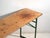 This antique beer garden table (bierzelt) in pine wood features a long solid pine top over x-shaped folding legs in green-...