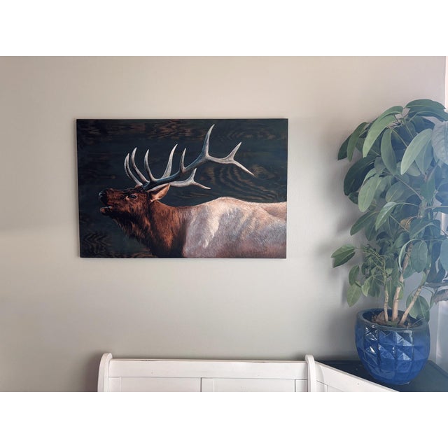 This oil painting captures a majestic elk in profile, its impressive antlers reaching skyward against a backdrop of rich,...