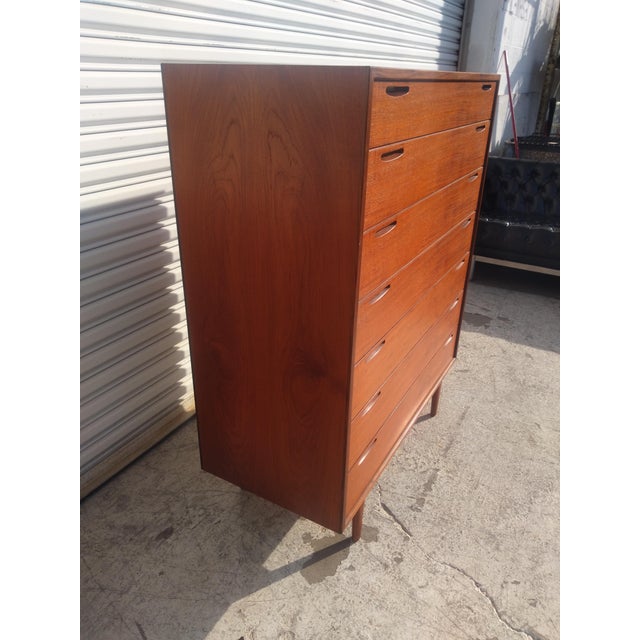A Mid-Century Modern chest of drawers featuring Danish modern styling in teak with seven drawers. This piece was made in...