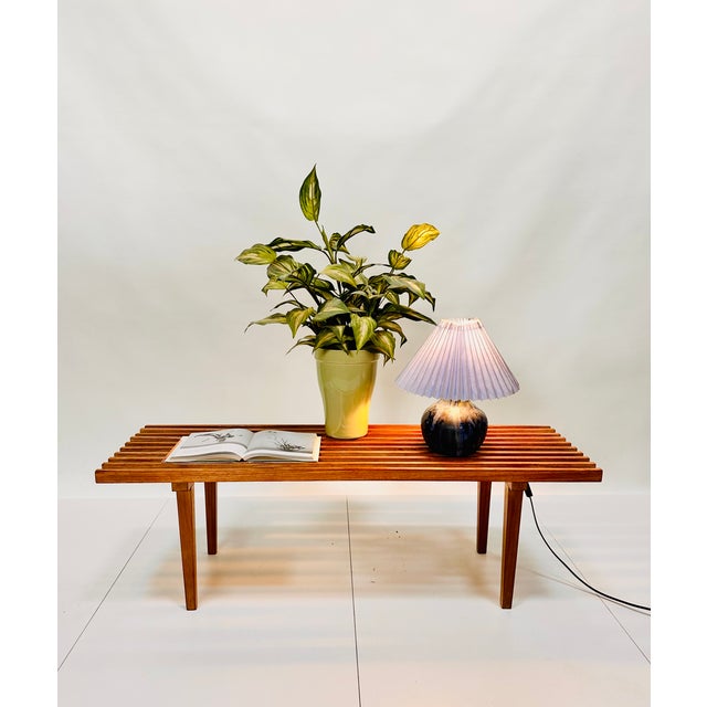 This minimalist design side table or flower bench with wooden slats in walnut shows a beautiful wood grain in warm tones....