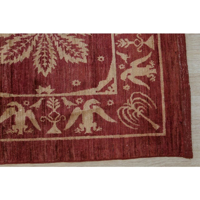 An 8' x 11' hand-knotted wool rug with a red field with an ivory lattice of flowers and birds, in a low, dense Afghan wool...