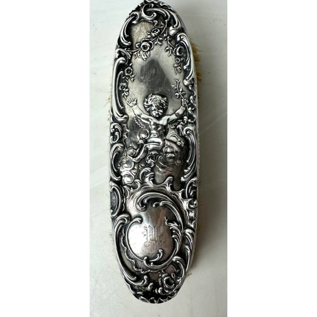 Exquisite Sterling silver ornate clothes brush with foliage and a cherub . Measures 7.5” x 2.25” x 2” . Hallmarked on side...