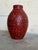 This striking ceramic floor vase features a vibrant red and black lava glaze with a bulbous silhouette. The bold texture...