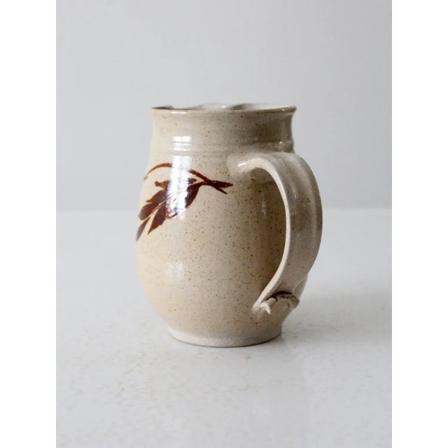 This is a vintage Lakeside Pottery pitcher. Signed by the artist, the handmade studio pottery ewer features a creamy beige...