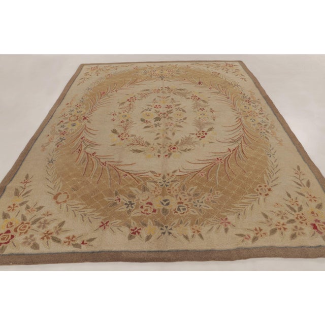 Handmade in wool, this 9x11 antique hooked rug dates to circa 1920-1930. The design features an elegant floral wreath...