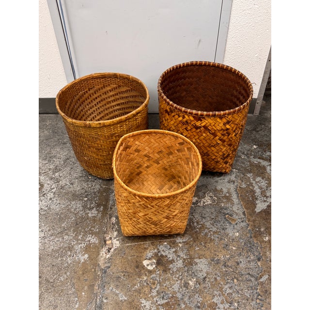 Design Plus Gallery presents a Set of Three Vintage Handwoven Wicker Baskets. Each basket has a rounded rim, tapered body,...