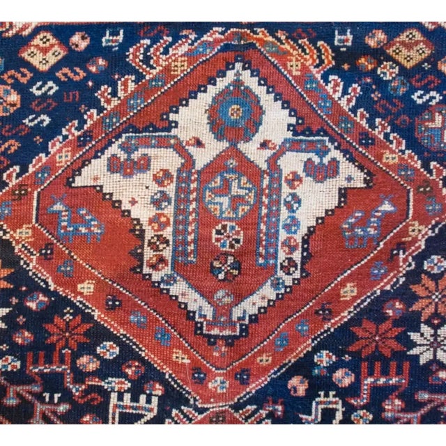 An incredible late 19th century Persian Ghashghaei rug with two large crimson and indigo diamond medallions amidst a...