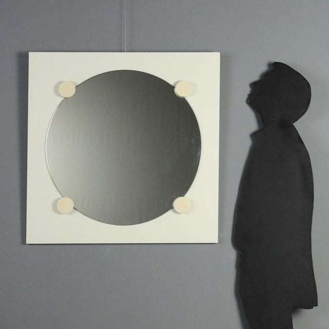 1970s wall mirror featuring a simple and linear design. Made of lacquered wood, it has a square frame enclosing an oval-...