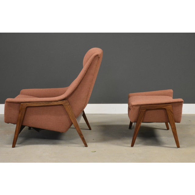 A mid century modern walnut frame lounge chair and ottoman designed by Folke Ohlsson for Dux in an orange checkered...