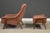 A mid century modern walnut frame lounge chair and ottoman designed by Folke Ohlsson for Dux in an orange checkered...