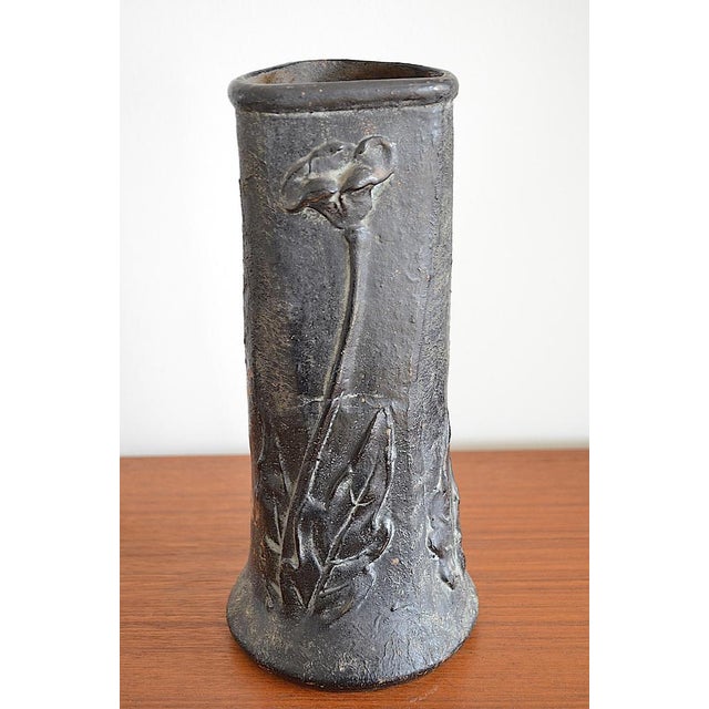 Art Nouveau flower vase with a continuous floral relief motif, cylindrical in shape, and a slightly flared base. The vase...