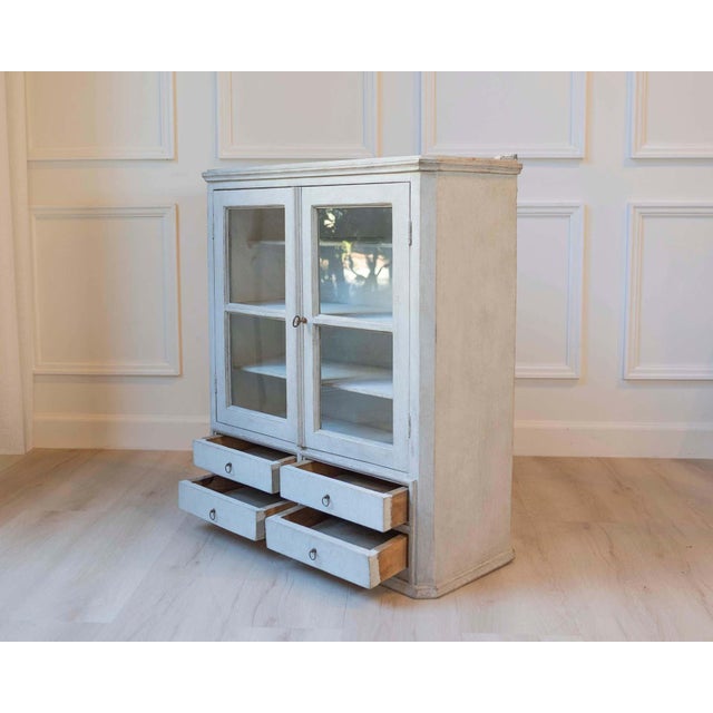 This Swedish hanging cabinet is crafted in pine and finished in a soft grey paint with a gentle patina that highlights its...