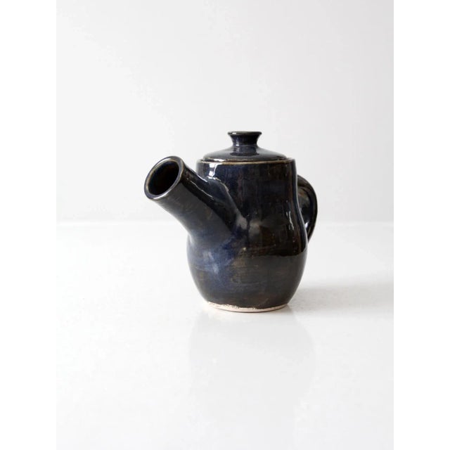 This is a signed studio pottery tea or coffee pot. The hand-crafted pottery server features a deep navy blue glaze with an...