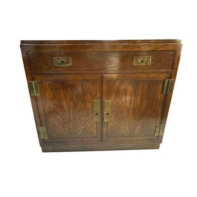 A handsome vintage Campaign style flip-top server and bar cabinet by Dixie Furniture, dating to the 1970s. Inspired by...