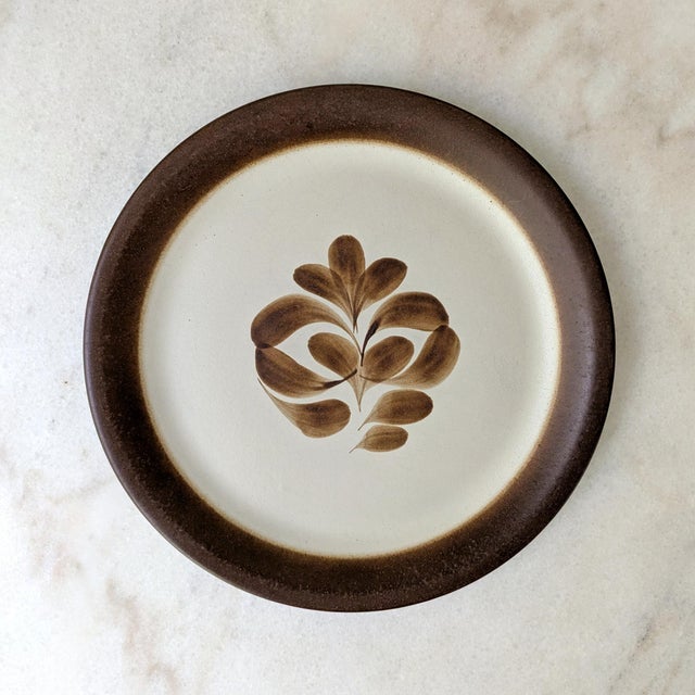 A set of four mid-century stoneware dinner plates featuring a hand-painted leaf design, made in Norway.