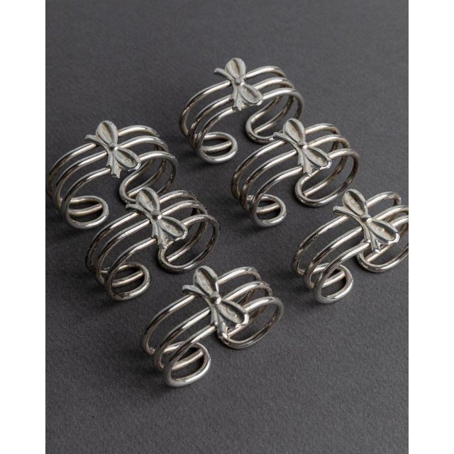 This vintage set of 6 silver-plated napkin rings from 1970s Italy features an elegant ribbon-shaped design with a...