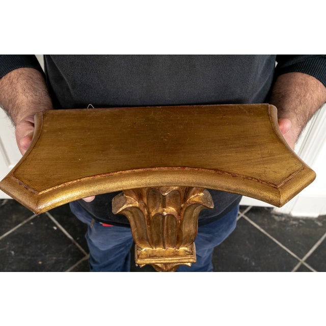 A vintage Italian carved and gilded wall bracket shelf with a rectangular shaped top and scrolling acanthus-leaf corbel...
