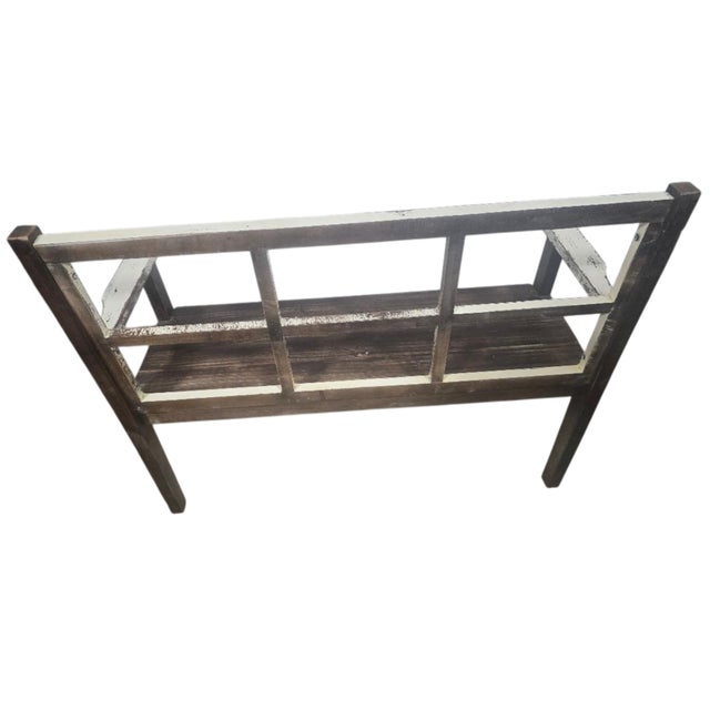 A distinctive rustic farmhouse bench featuring an architectural window-frame back, a dark-stained wooden seat and...