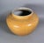 A rounded ceramic vessel finished in a warm mustard glaze, decorated throughout with finely incised floral and scrolling...