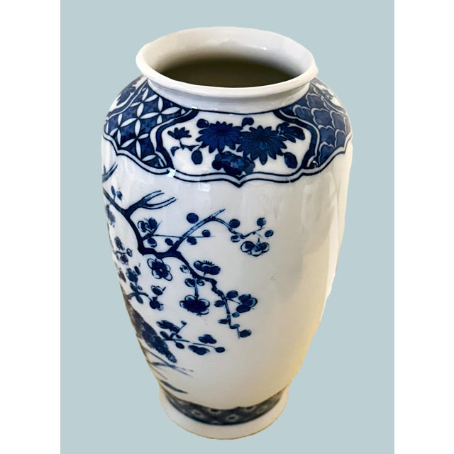 A striking vintage Japanese porcelain vase featuring a beautifully rendered peacock surrounded by lush florals, all...