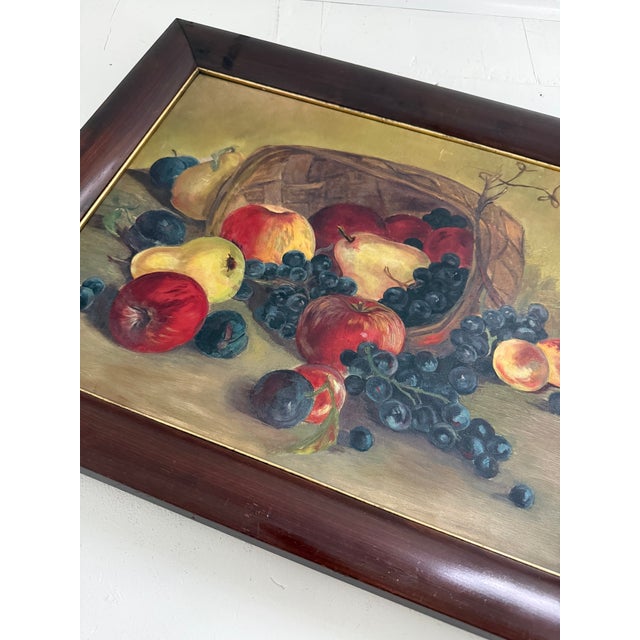 Late Victorian oil on canvas still life depicting a woven basket tipped on its side, spilling apples, grapes, plums and...