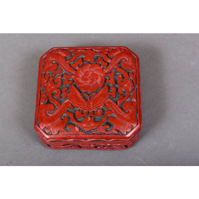 A pair of small antique Chinese decorative covered boxes: a deeply carved cinnabar lacquered box with an intricate lotus...