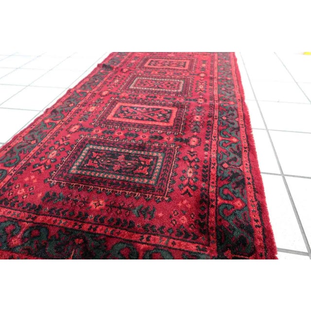 Vintage red woolen rug from Germany made in Baluch style. The rug is in deep red and emerald shades. It is from the middle...