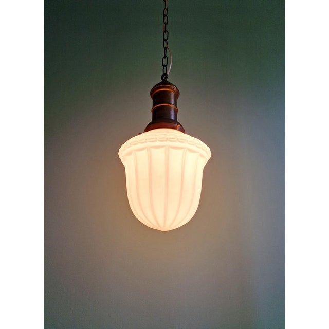 Art Deco pendant light in pressed molded white glass with a copper-plated metal frame, 1920s-30s. The pendant light has...