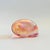 A vintage art glass paperweight in the shape of a shell. Iridescent pink color to the glass. Measures 3.5"W x 2"D x 2"H
