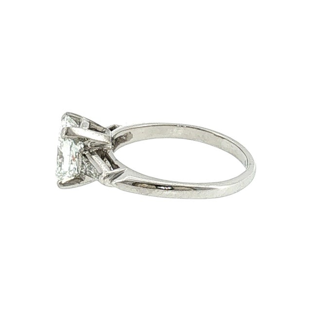 A platinum 1950's bridal ring featuring a repurposed radiant-cut diamond. The diamond weighs 1.28 carats and has a clarity...