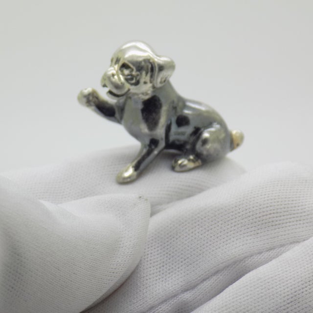 This vintage silver decorative object depicts a puppy dog figurine miniature with a raised paw, crafted as a dollhouse...
