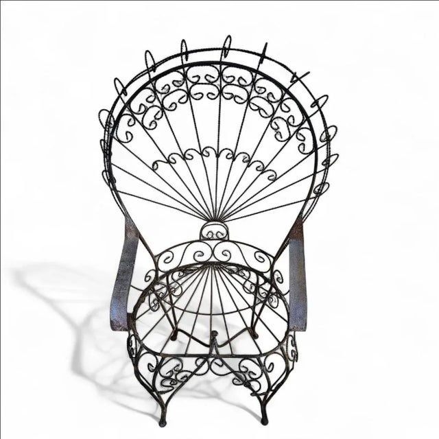 This monumental vintage wrought iron peacock chair, in the Salterini style, features an exaggerated fan back with...