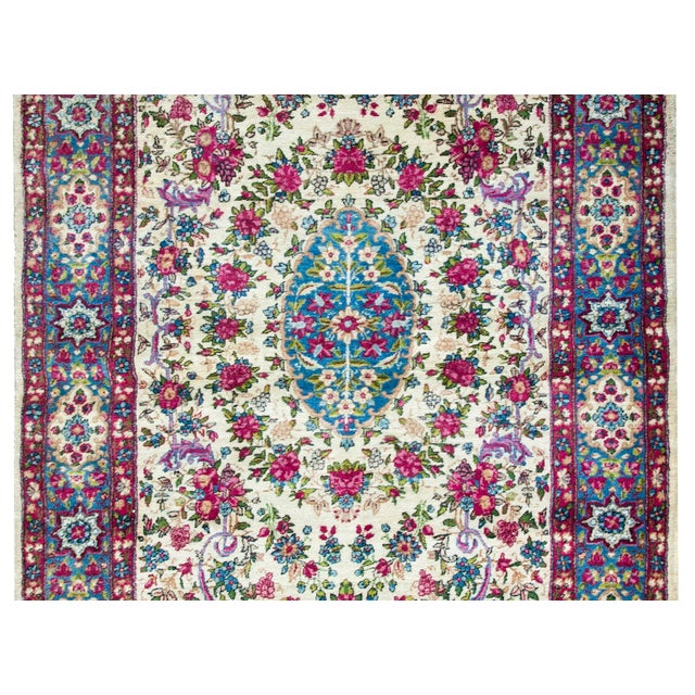 A sweet early 20th century Persian Kirman rug with a stunning pattern with myriad flowers woven in pinks, fuchsias,...