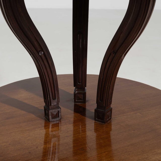 Round pedestal center table in Rich Mahogany. Its rich mahogany finish sets off scrolled tripod base, glass-topped...