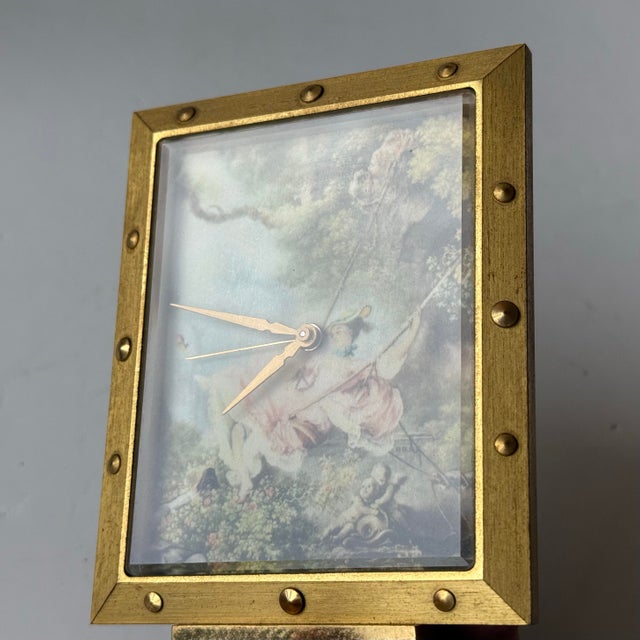 Vintage decorative brass boudoir desk clock. The clock face features an art print of “The Swing” by Fragonard. Mechanical...
