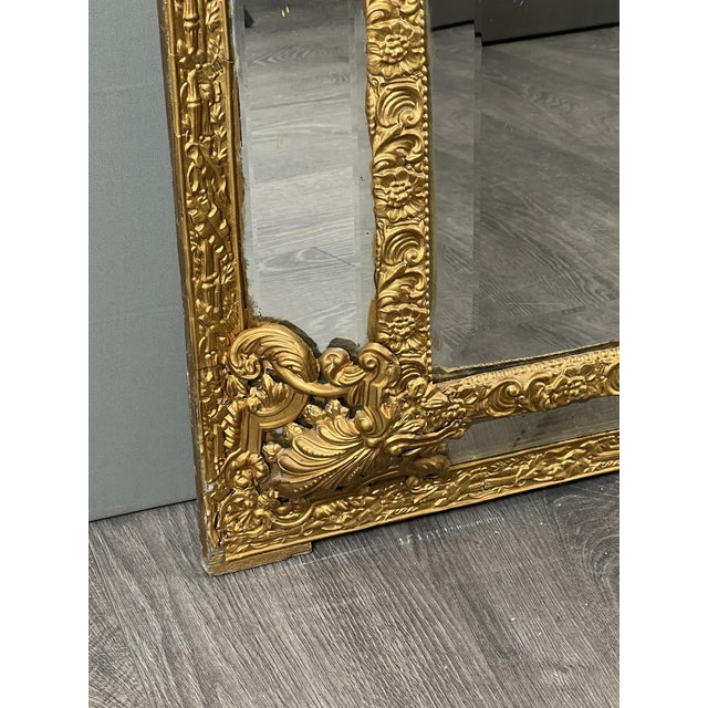 Important antique wall mirror in finely crafted and gilded metal. The richly openwork pediment features scrolls, foliage,...