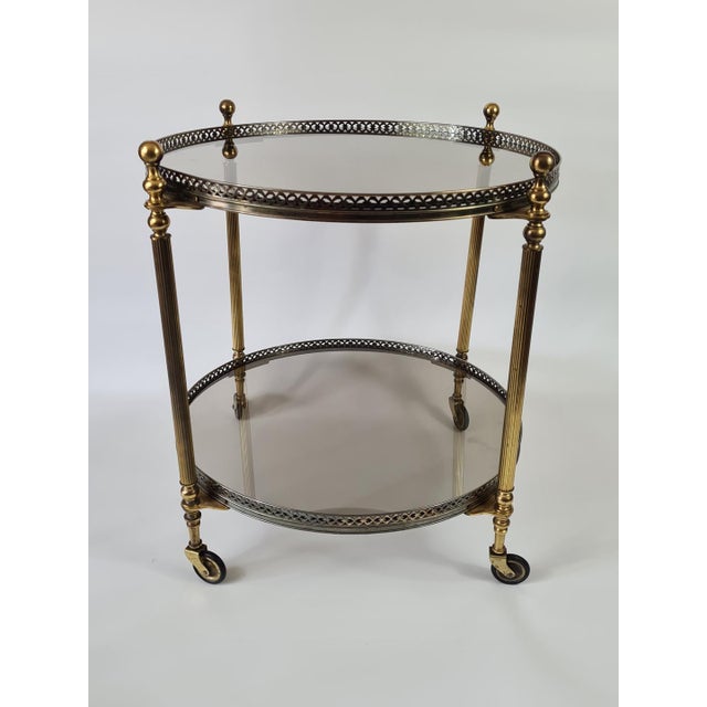An elegant vintage serving/bar table on wheels, made of brass and featuring two panels of mirrored glass. The piece is...