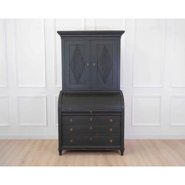 A beautifully crafted Swedish Gustavian style roll top secretary cabinet finished in a rich hand-painted black that...