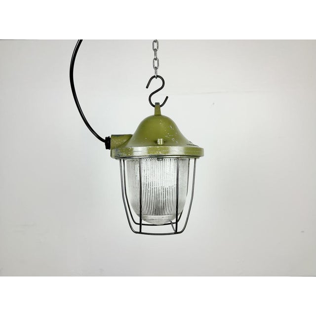 Green industrial lamp made by Polam Gdansk in Poland during the 1960s. It features a cast aluminium body, an iron cage and...