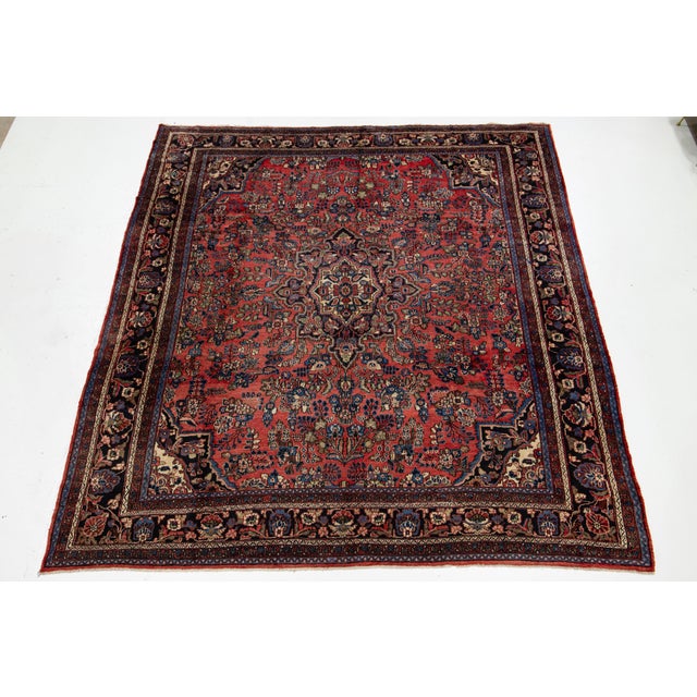 This Persian Hamadan wool rug features a rich red background adorned with multicolored accents, showcasing an intricate...