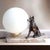 A signed vintage tedd table lamp pairing a seated german shepherd with a luminous white opaline glass globe on a veined...