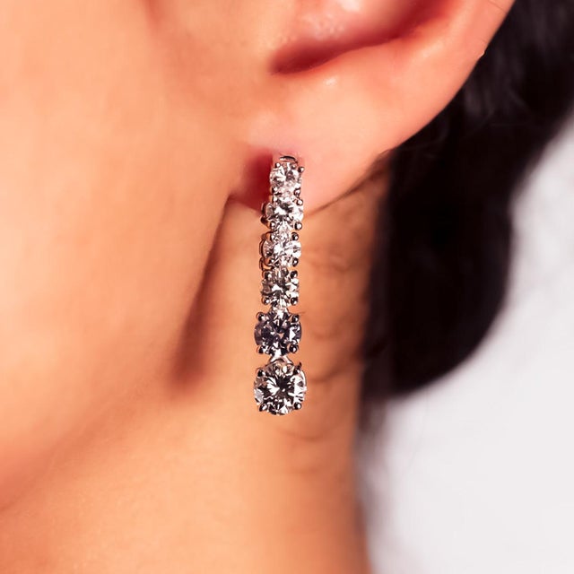 14k White gold earrings with 12 round brilliant diamonds weighing approximately 5.25 carats with the two largest diamonds...